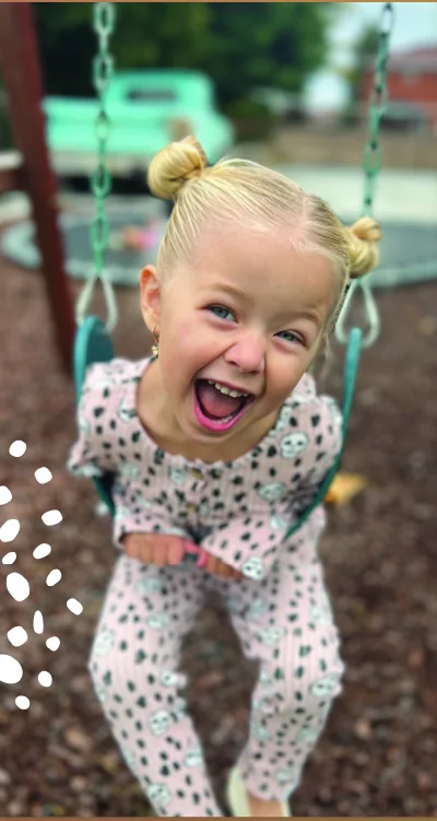 A Blissful Beginnings student smiling while playing on a swing